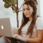 woman researching on a laptop while sitting on a sofa